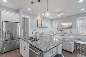 A modern kitchen with a stainless steel refrigerator, granite countertops, and pendant lighting. - 6-Seater Golf Cart & 6 Bikes! Newly Furnished! 2 Resort Pools! Sunset at Seagrove on 30A (Santa Rosa Beach)