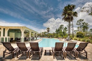 Un área junto a la piscina con sillones de descanso y una zona de estar cubierta.