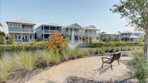 A beachfront property with multiple two-story houses, a sandy beach, and a small pond. - 6-Seater Golf Cart & 6 Bikes! Newly Furnished! 2 Resort Pools! Sunset at Seagrove on 30A (Santa Rosa Beach)