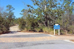 Un sendero pavimentado que conduce a un cartel indicador de la ruta de la playa.