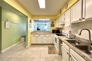 Kitchen features a central island with appliances, double sink, and ample storage.