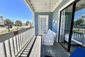 Enjoy the view from this balcony with a comfortable bench, overlooking the street lined with palm trees.