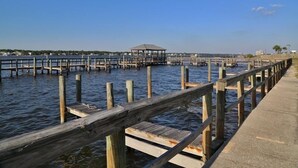Un muelle de madera que se adentra en aguas tranquilas, con un pabellón al final.
