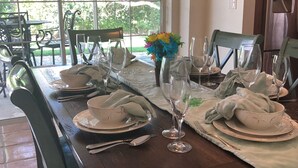 A dining table set with plates, glasses, and cutlery, with chairs around it. - Updated and Spacious 3 Bed 2 BA Home, Heated Pool, 4 Bikes, 5 Min Walk to Beach  (Marco Island)