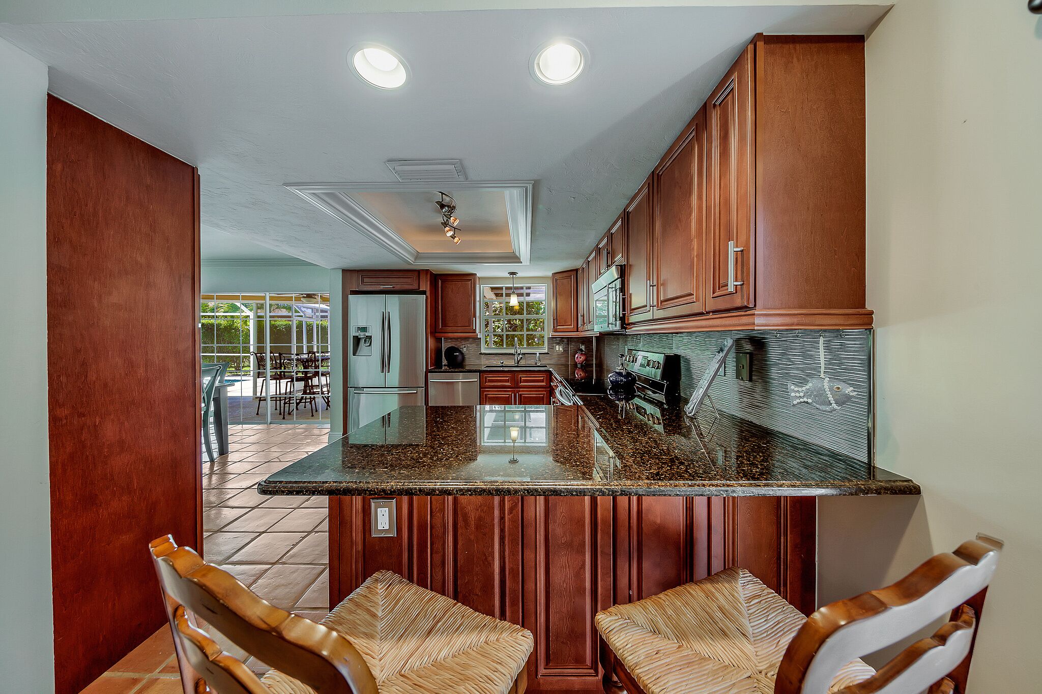 A kitchen with wooden cabinets, a granite countertop, and a dining area with wicker chairs.