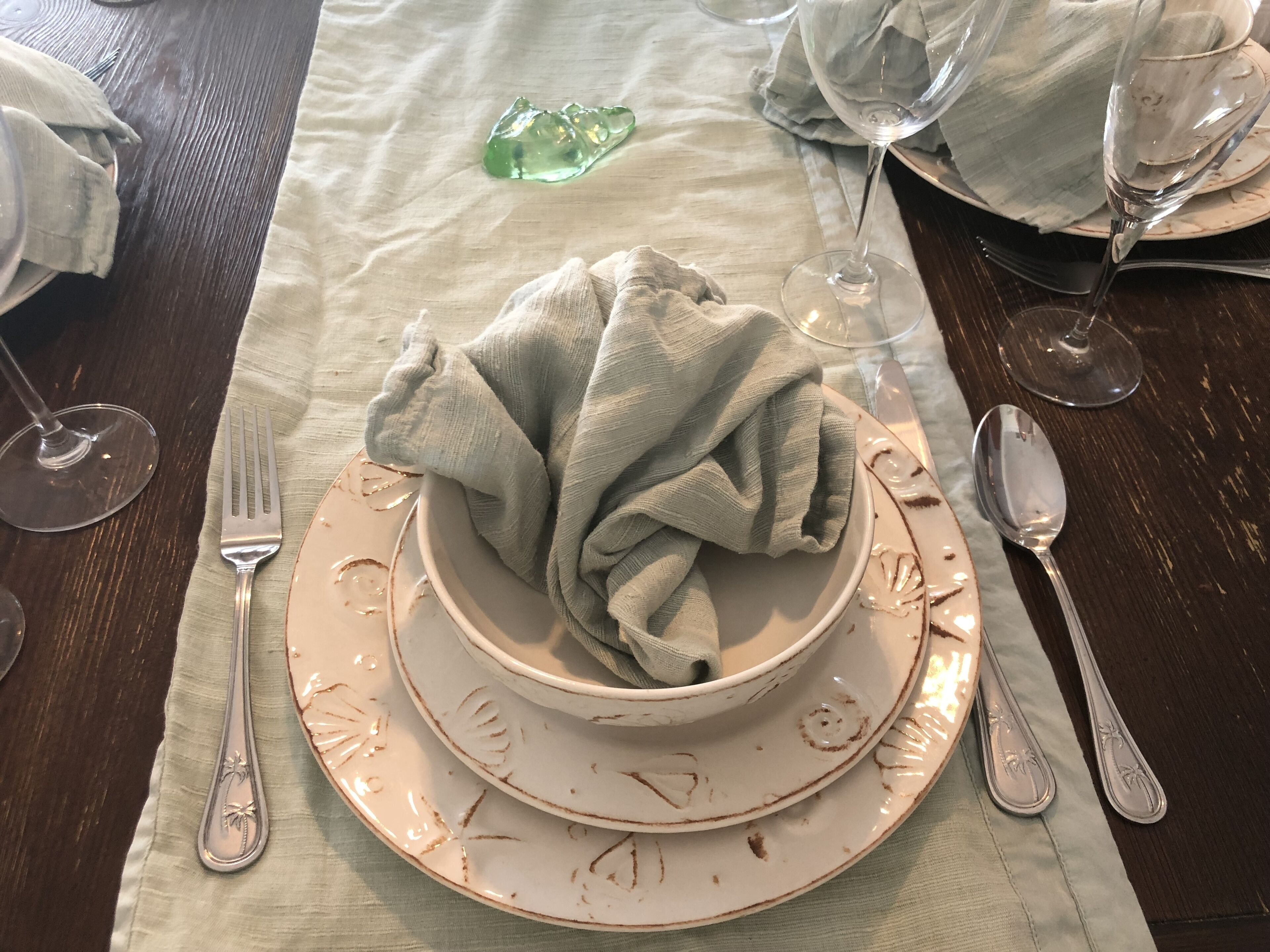 A table set with a bowl, plates, cutlery, and a cloth napkin.