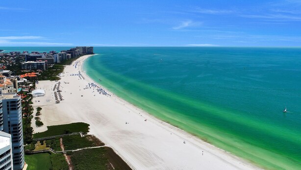 A coastal cityscape with a long sandy beach, clear blue waters, and high-rise buildings along the shore. - Updated and Spacious 3 Bed 2 BA Home, Heated Pool, 4 Bikes, 5 Min Walk to Beach  (Marco Island)