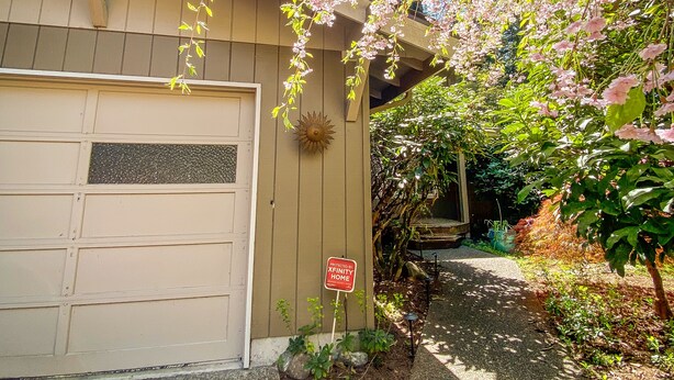 A residential garage with a 'For Sale' sign, a driveway, and a garden with flowering trees. -  Foodies Kitchen, Peaceful, Green, Comfiest Beds, Close to everything   (Olympia)