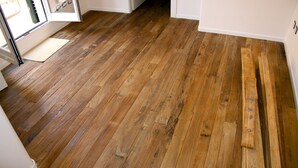 Ein Holzboden mit einer Tür und einer Matte im Vordergrund.