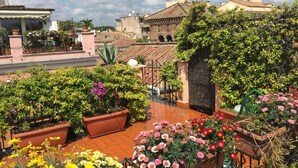 Ein Dachgarten mit Kübelpflanzen und Blumen, einer Pergola und Blick auf die Stadtlandschaft.