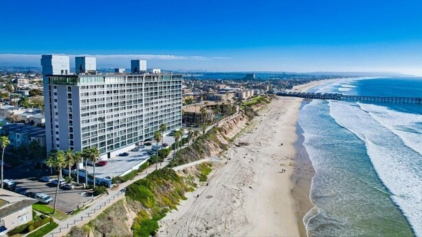 A high-rise hotel with multiple floors, a beach view, and a pier extending into the ocean. - Pacific Beach Escape | Walk to Ocean | Private Yard | A/C | Dogs OK (San Diego)