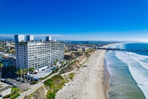 Un hotel moderno de gran altura, con varias plantas, vistas a la playa y un muelle que se adentra en el océano.