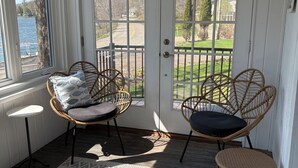 Een veranda met rieten stoelen, een klein tafeltje en een kamerkleed met dessin.