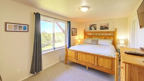Une chambre à coucher avec un lit en bois, une fenêtre avec des rideaux, une table de chevet avec une lampe et des œuvres d’art accrochées au mur.