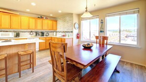 Une cuisine avec des meubles en bois, un grand îlot central et un coin repas avec une banquette.