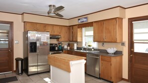Una cocina con armarios de madera, un refrigerador de acero inoxidable, un lavavajillas y una encimera de madera.
