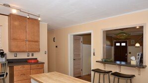 Una cocina con armarios de madera, una encimera y dos taburetes de bar.