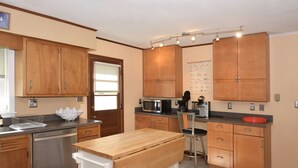 Una cocina con armarios de madera, microondas, cafetera y lavamanos.