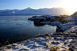 A snowy landscape with mountains in the background and a frozen body of water in the foreground. - Art and nature retreat  (Borgarnes)