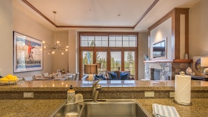 A modern kitchen with granite countertops, a stainless steel sink, and a stone fireplace. - Luxury 3BD Village at Northstar Residence - Iron Horse North 101 (Truckee)