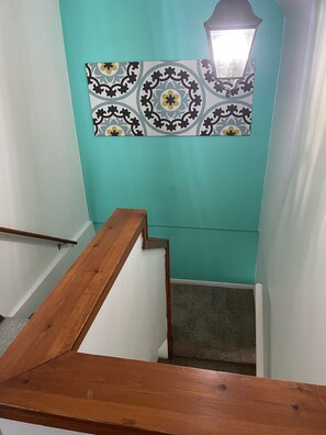 Stairs lead to a landing with a decorative tile above, featuring a small window with a frosted glass cover.