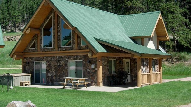 Un chalet doté d’une façade en pierre, de grandes fenêtres et d’un toit végétalisé.