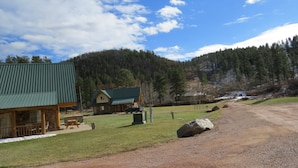 Un chalet doté d’un toit végétalisé, d’un porche abrité et d’une allée en gravier menant à un paysage montagneux.