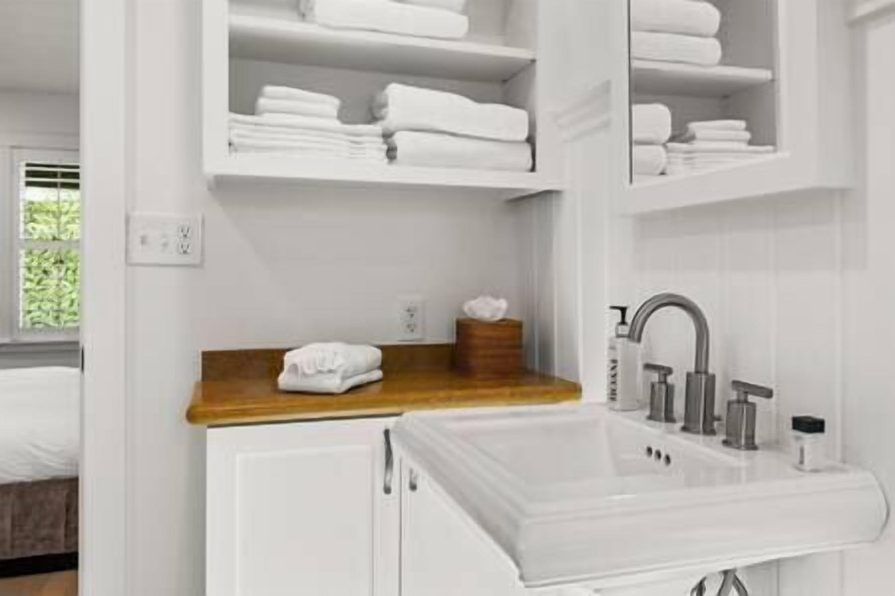 A bathroom with white cabinetry, a wooden countertop, and a sink with a modern faucet.