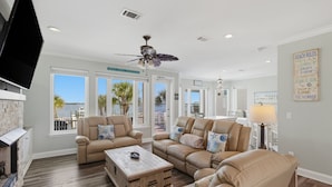 A spacious living room with a fireplace, beige sofas, a wooden coffee table, and a ceiling fan. - Navarre Beach Southside bring your boat and jet skis huge private pier (Navarre)