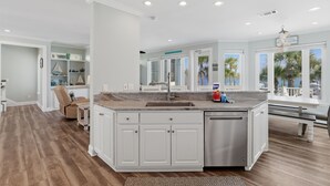 A spacious kitchen with a large island, white cabinetry, and a view of palm trees through the windows. - Navarre Beach Southside bring your boat and jet skis huge private pier (Navarre)