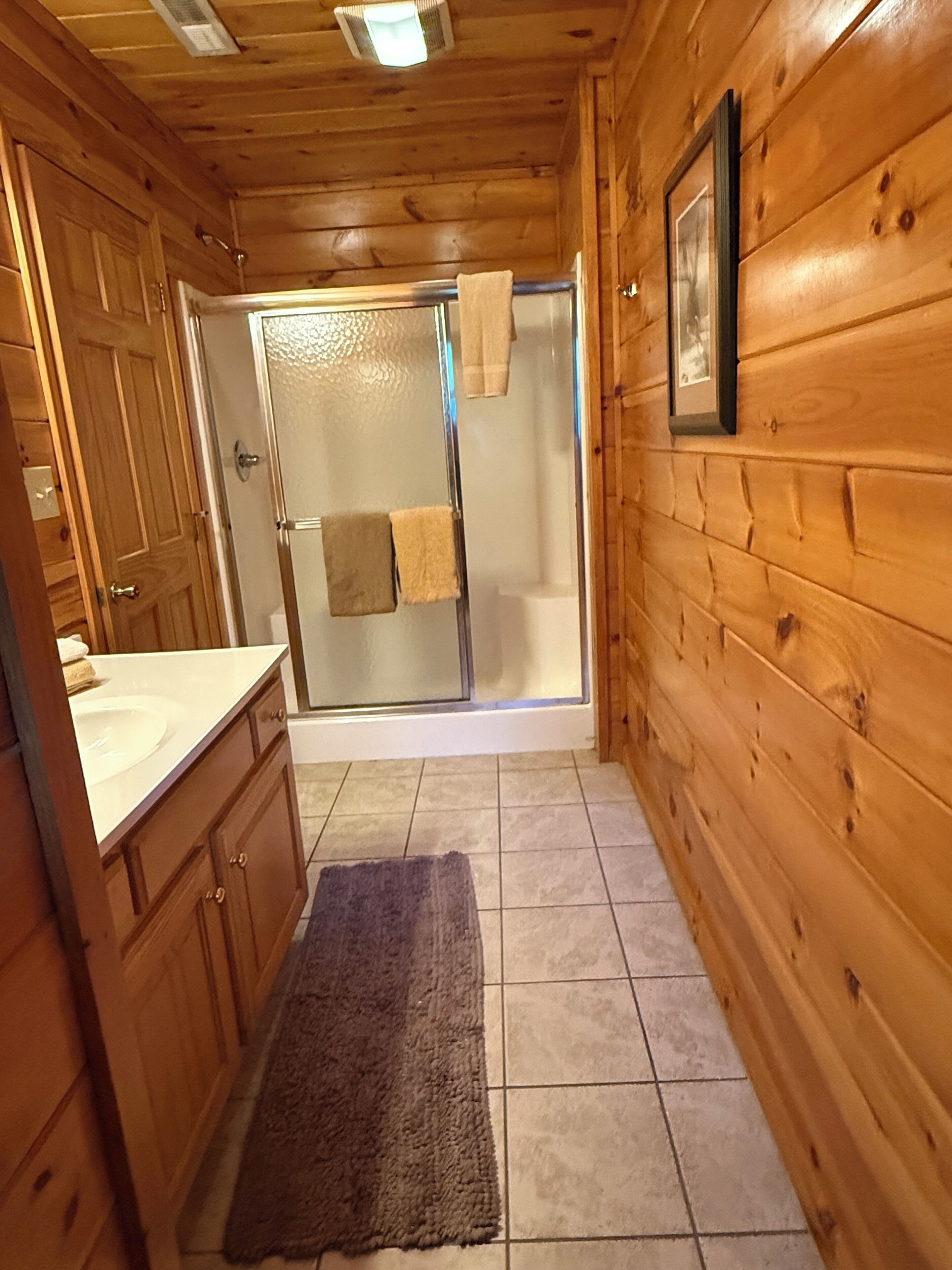 A wooden cabin bathroom with a shower, a sink, and a toilet.