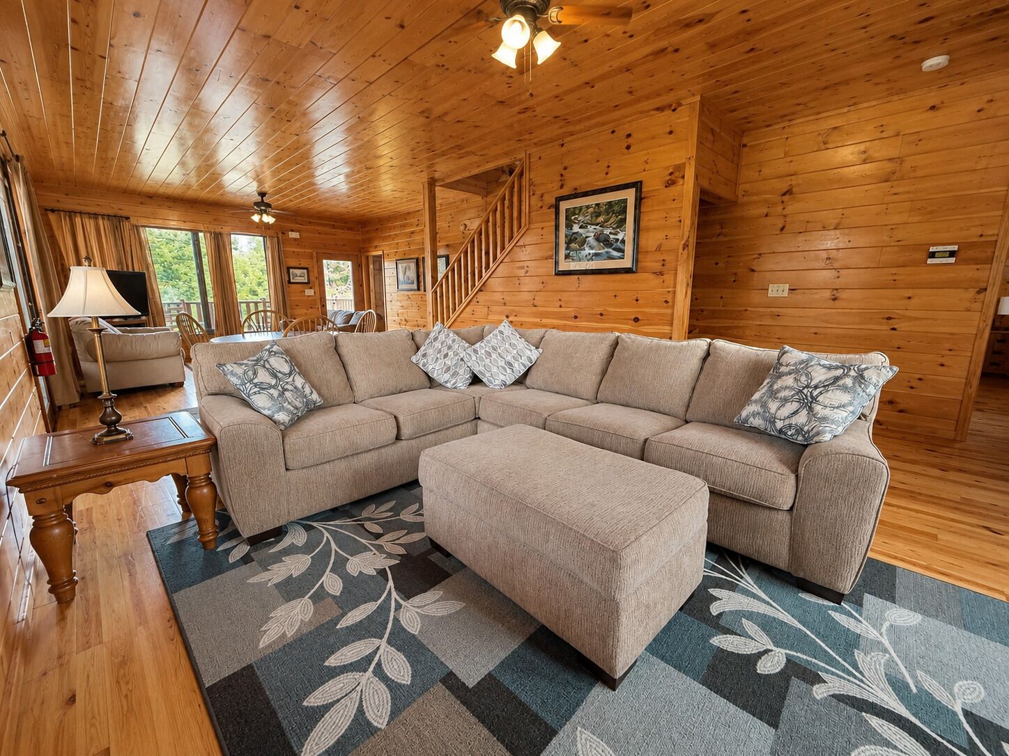 A wooden interior with a sofa, ottoman, and a staircase.
