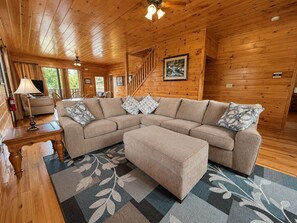 A wooden interior with a sofa, ottoman, and a staircase. - 6 BD 6 BATH ALL Ensuite cabin. Come make memories for a lifetime! (Sevierville)