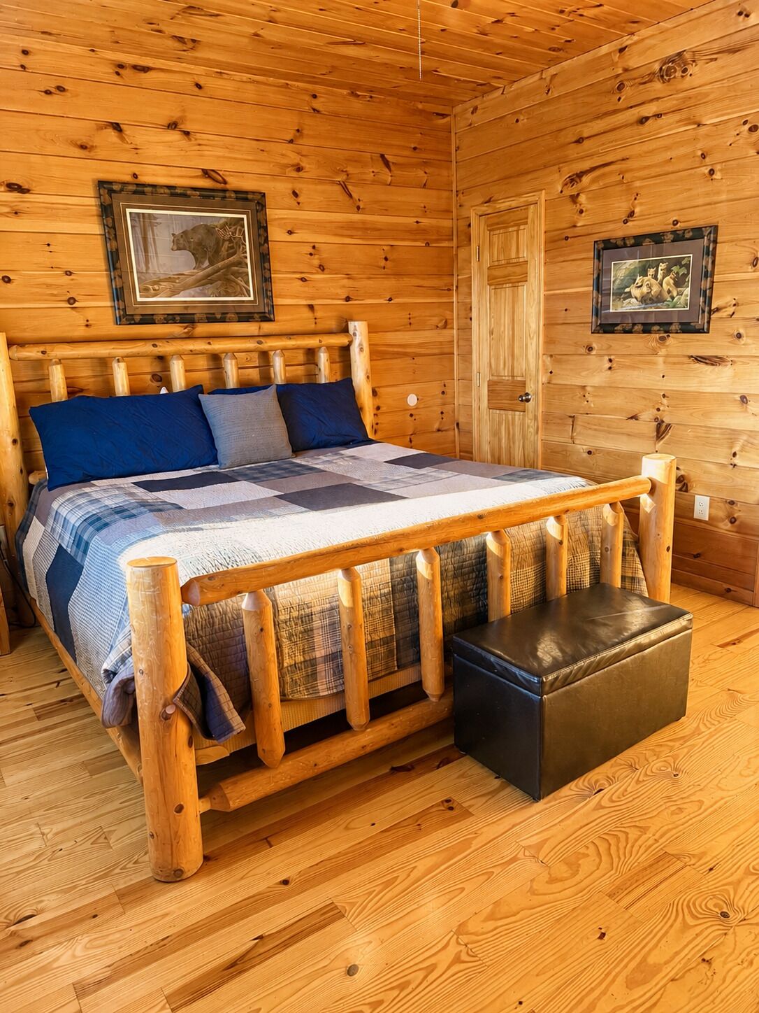 Una camera in legno con un letto, una panca e due quadri appesi alle pareti.
