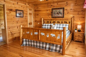 A wooden cabin bedroom with a bed, a nightstand, and a wall with animal prints.