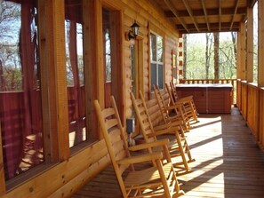 Une cabane en bois dotée d’un porche avec des fauteuils à bascule en bois et un jacuzzi.