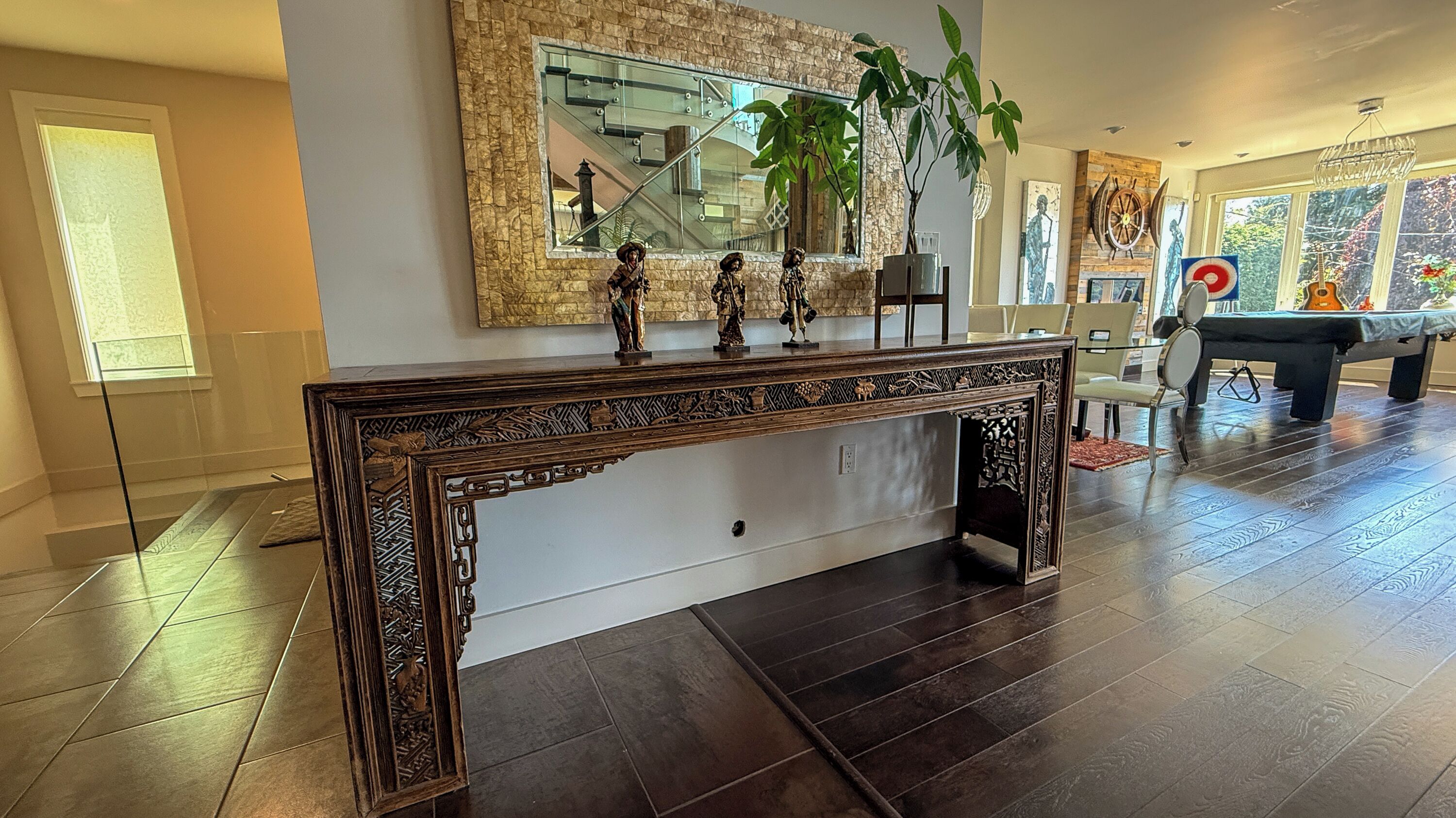 Un salon moderne avec une console en bois foncé, un grand miroir et un escalier.