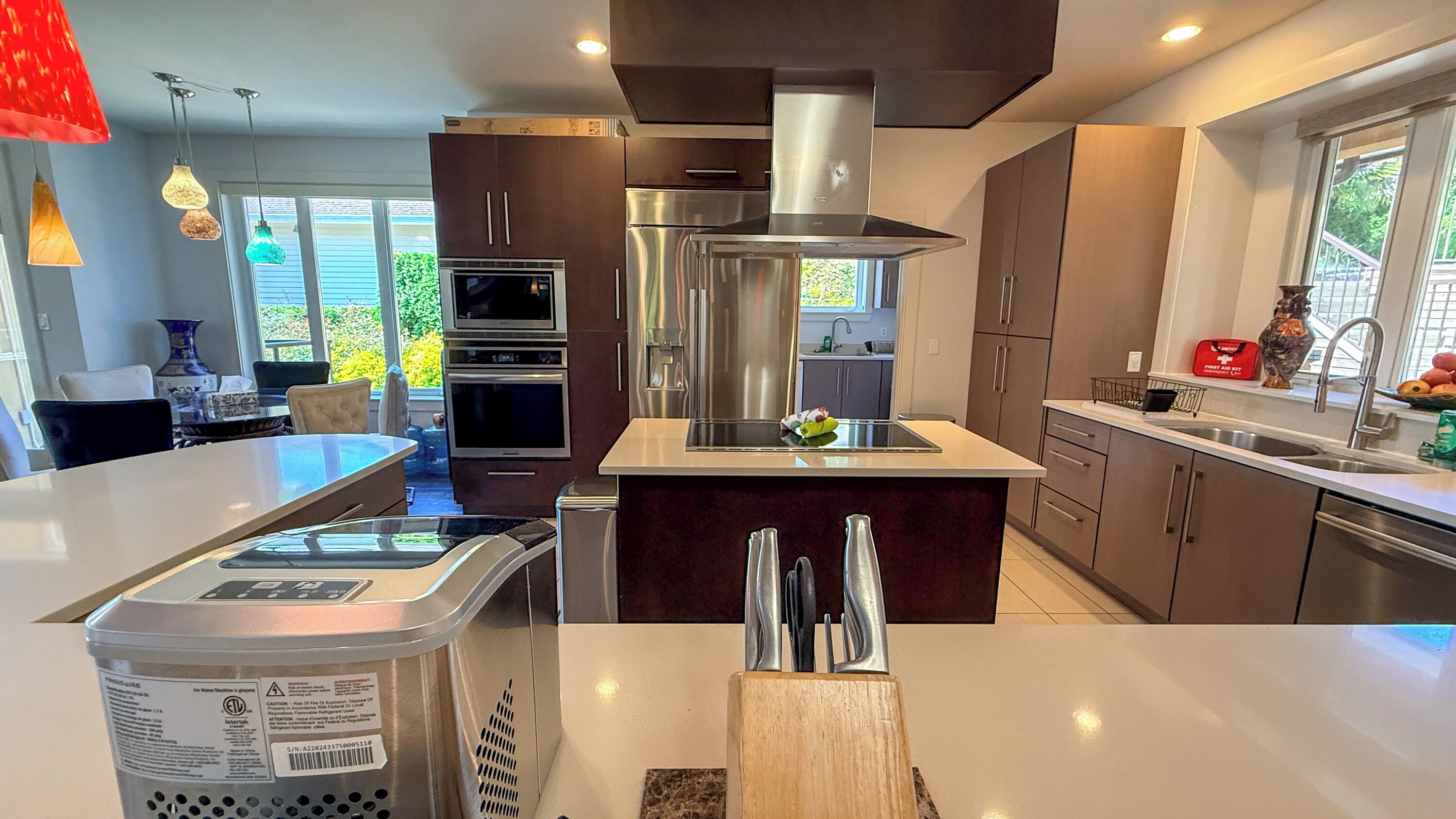 A modern kitchen with stainless steel appliances, a central island, and a dining area with a table and chairs.