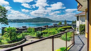 Uma varanda com vista para um lago e uma colina arborizada.