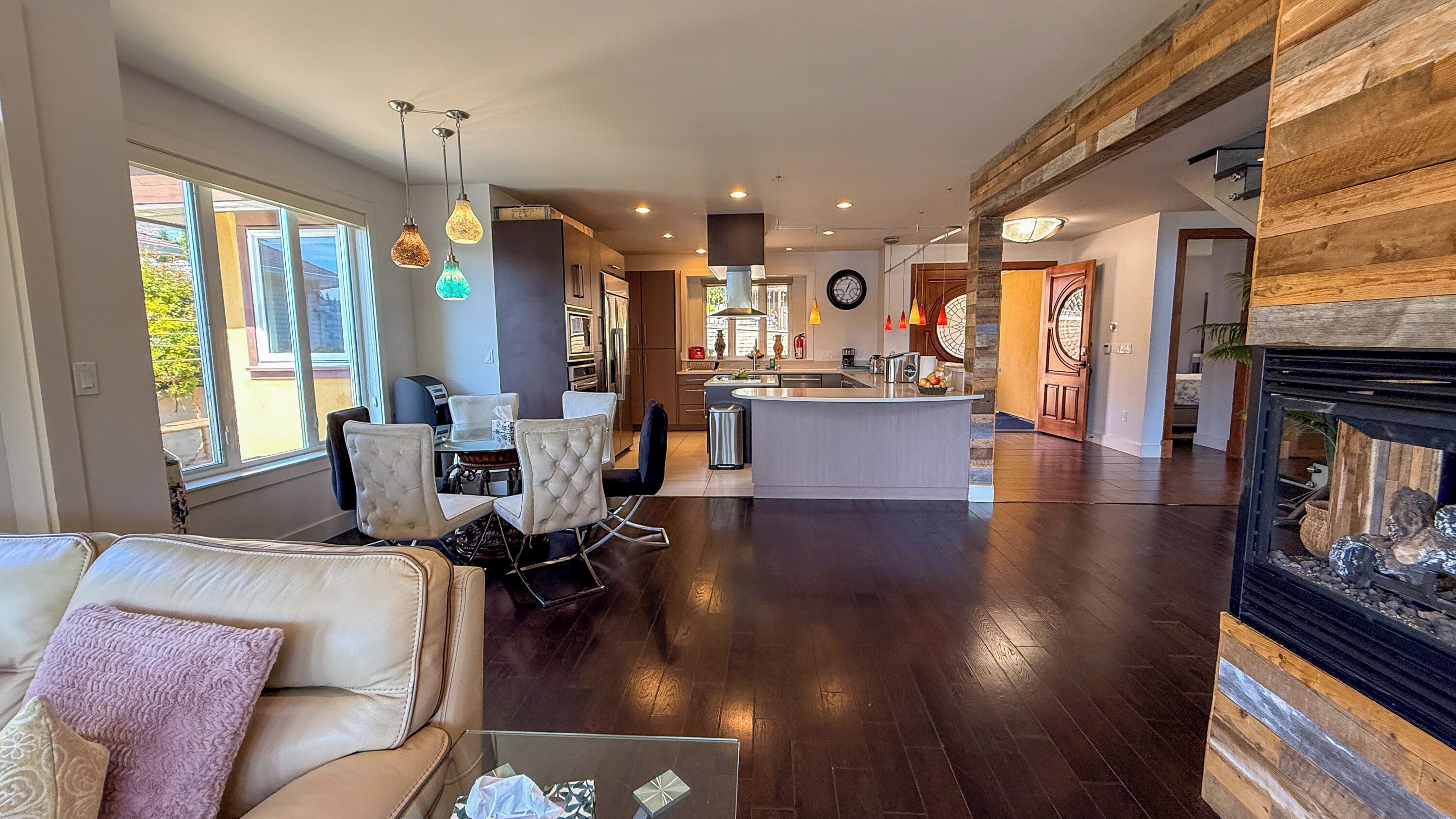 A spacious living area with a sofa, dining table, and chairs, a kitchen with modern appliances, and a fireplace.