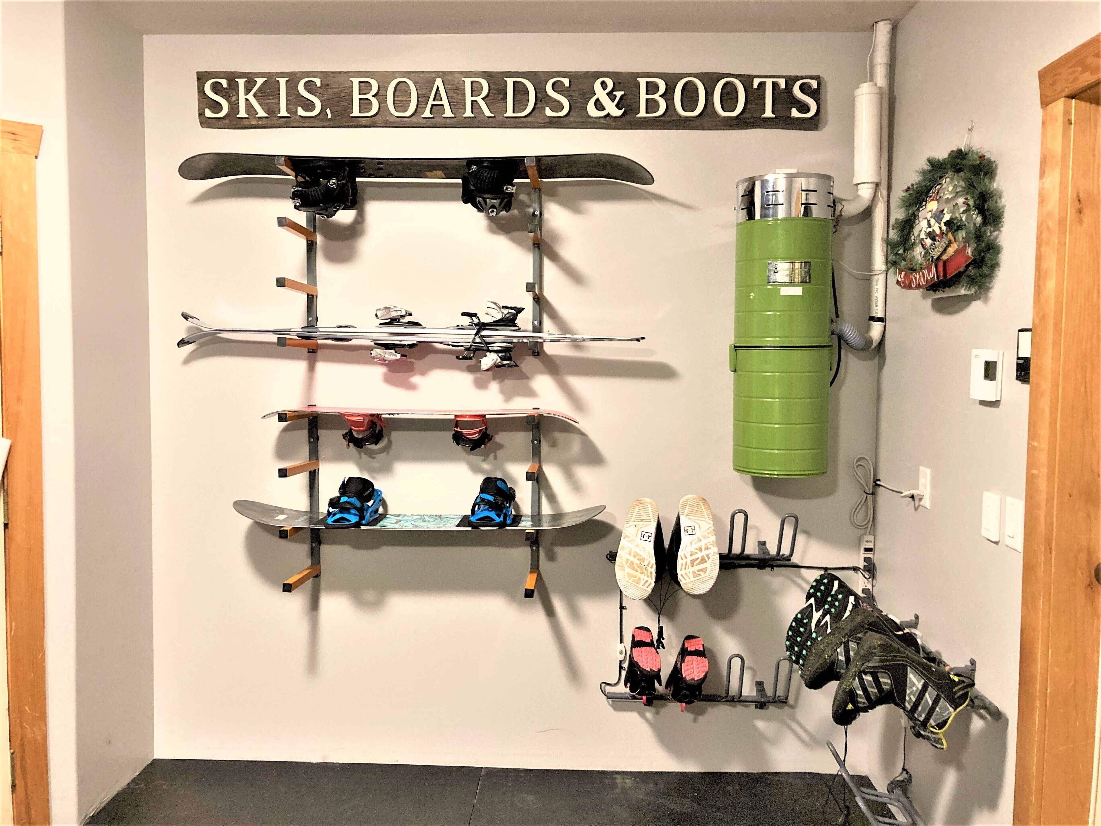 A wall-mounted rack with skis, boards, and boots.