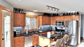 Eine moderne Küche mit Holzschränken, Edelstahlgeräten und einer zentralen Kochinsel mit Barhocker.
