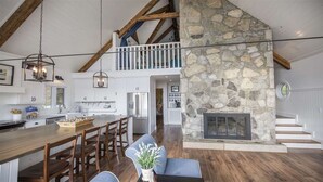 A spacious kitchen with a central island, wooden dining chairs, and a stone fireplace. - Perfect Location For Your Lake Getaway (Cadiz)