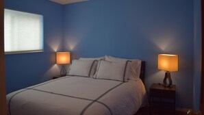 A bedroom with a bed, two bedside lamps, and a window with blinds. - Park like setting, brand new built, 1 bedroom ADU (Shoreline)