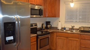 A kitchen with wooden cabinets, stainless steel appliances, a microwave, a coffee maker, and a window with blinds. - Park like setting, brand new built, 1 bedroom ADU (Shoreline)