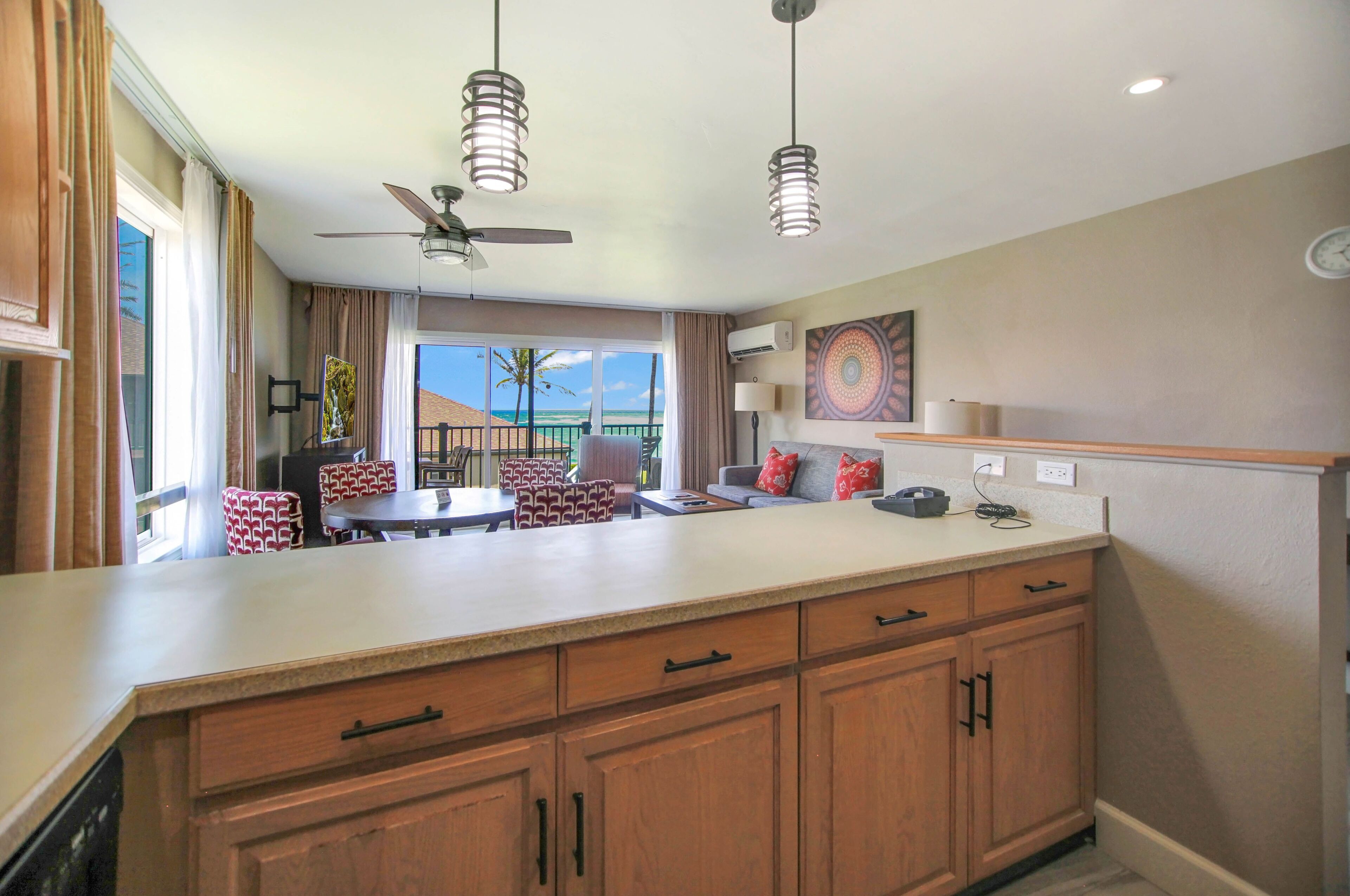 Una cocina moderna con una isla central, armarios de madera e iluminación colgante.