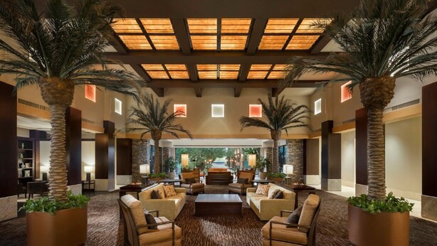 A spacious lobby with a central seating area, palm trees, and a view of the outdoors. - Confirmed Reservation - March 13–20, 2027 - 1BR Premium Villa - Instant Book (Scottsdale)