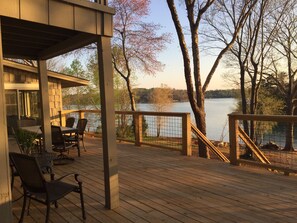 A wooden deck with outdoor seating, overlooking a lake and trees. - Pristine views from Lakefront Home  (Seneca)