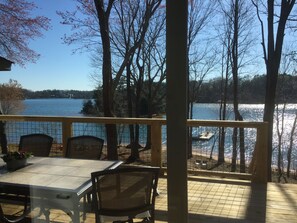 A covered outdoor seating area with a table and chairs, overlooking a lake with trees and a dock. - Pristine views from Lakefront Home  (Seneca)