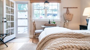 A bedroom with a bed, a window with a view, a chair, and a table. - Hagan's Hideaway (Encinitas)